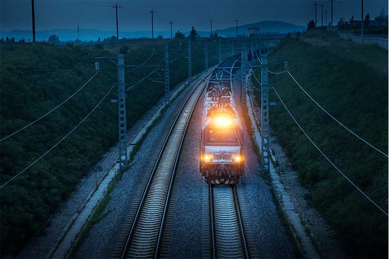 High-speed freight train on railway tracks during dusk, representing efficient logistics and transportation solutions by China Vast Logistics.
