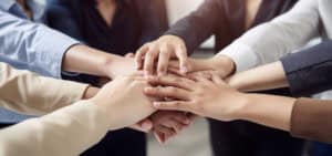 Team members stacking hands together in a gesture of unity and collaboration, symbolizing teamwork, trust, and strong business partnership
