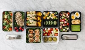 Miniature salad and snack containers with fresh vegetables, sushi, and fruits, showcasing diverse catering options from China Vast Logistics.