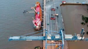 Cargo ship docked at port with loading cranes for international logistics and freight shipping.