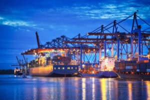 Container cargo ship at a busy port in China with cranes, emphasizing logistics, shipping, and transportation services.