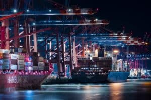 Container ships docked at a brightly lit Chinese port with cranes, showcasing logistics and freight transportation services.