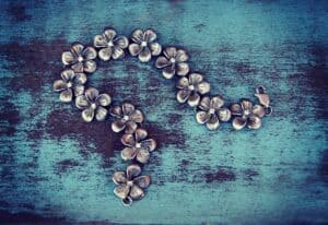 Shiny silver flower-shaped jewelry with diamond accents arranged in a question mark shape on a rustic blue wooden surface. Perfect for jewelry or fashion accessories.