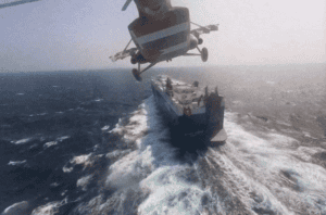 Helicopter delivering cargo to a large container ship at sea during daytime, illustrating China Vast Logistics maritime transportation services at sea, aerial cargo delivery, and logistics solutions in maritime industry.
