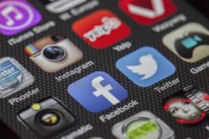 Social media icons on smartphone screen, including Facebook, Twitter, Instagram, and YouTube, close-up image emphasizing digital communication and online marketing for China Vast Logistics.