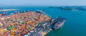 Container port filled with colorful shipping containers and cranes at a busy Chinese logistics hub overlooking the ocean, emphasizing large-scale freight and supply chain management.