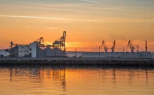 Industrial port at sunset with cranes and storage tanks in China, showcasing Vast Logistics shipping and logistics services optimized for international freight and container transportation.