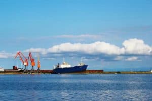 Cargo ship docked at port with cranes, representing China Vast Logistics and international shipping services.