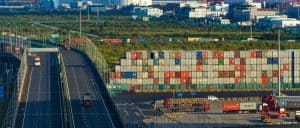 Container port with stacked shipping containers and active freight trucks, showcasing China Vast Logistics' efficient supply chain and freight forwarding services in China.