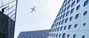 Aerial view of modern skyscrapers in China with a plane flying overhead, symbolizing global logistics and transportation services.
