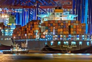 Container cargo ship at night, showcasing logistics and transportation services at China Vast Logistics, with brightly lit containers and port infrastructure.