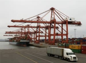 Container terminal with cranes, cargo ship and freight truck at port operations