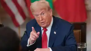 Large image of former US President Donald Trump speaking passionately during a meeting or interview, with flags in the background.
