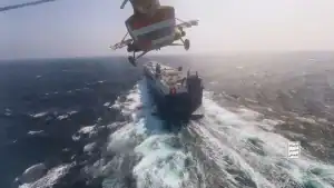 Aerial view of a helicopter delivering supplies to a cargo ship at sea, showcasing shipping and logistics operations.