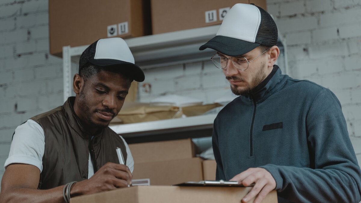 Two logistics workers reviewing a shipment handover document in a warehouse