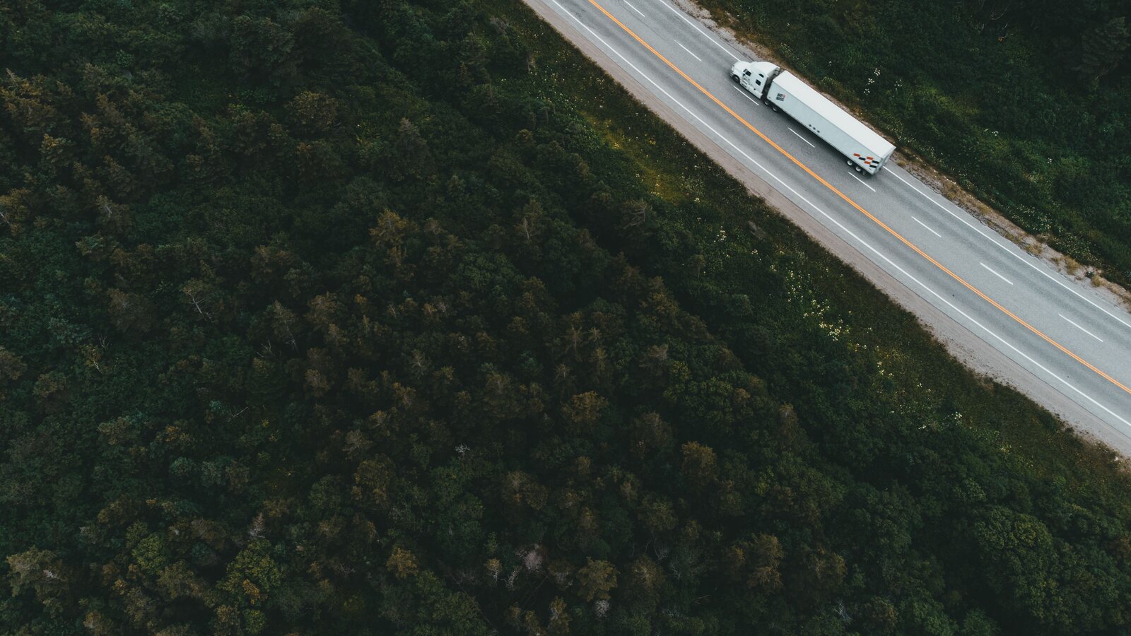 集装箱卡车行驶在公路上,示意取消订舱后的退柜与运输调整