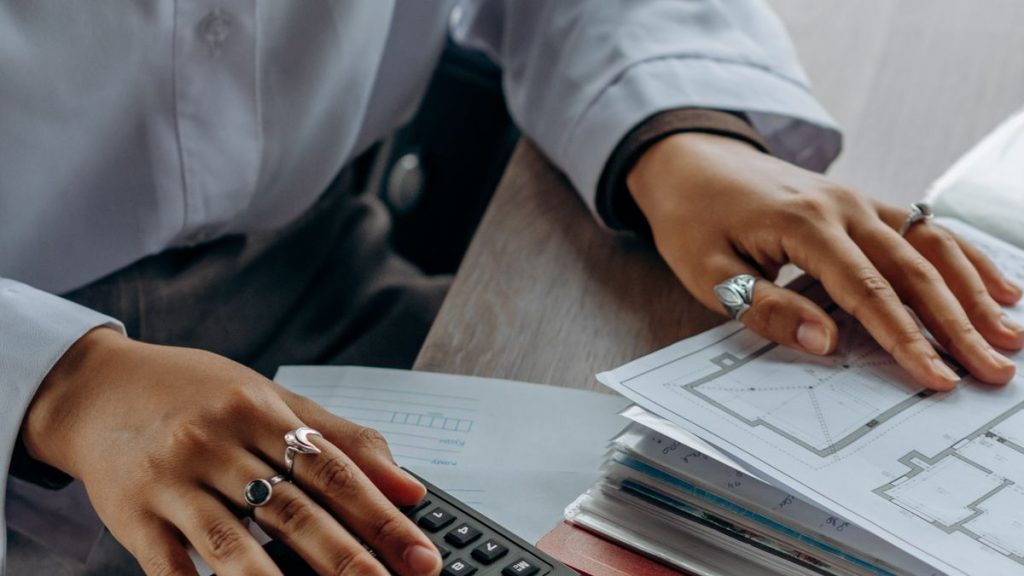 Hands reviewing documents beside a calculator on an office desk