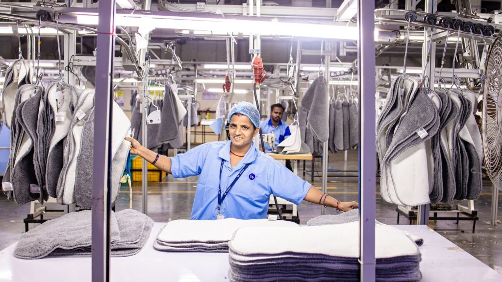 Factory quality control worker inspecting finished textile products before shipment