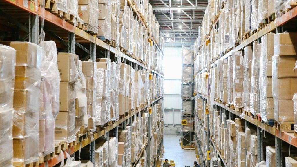Cardboard cartons stored on warehouse racks beside an inventory aisle
